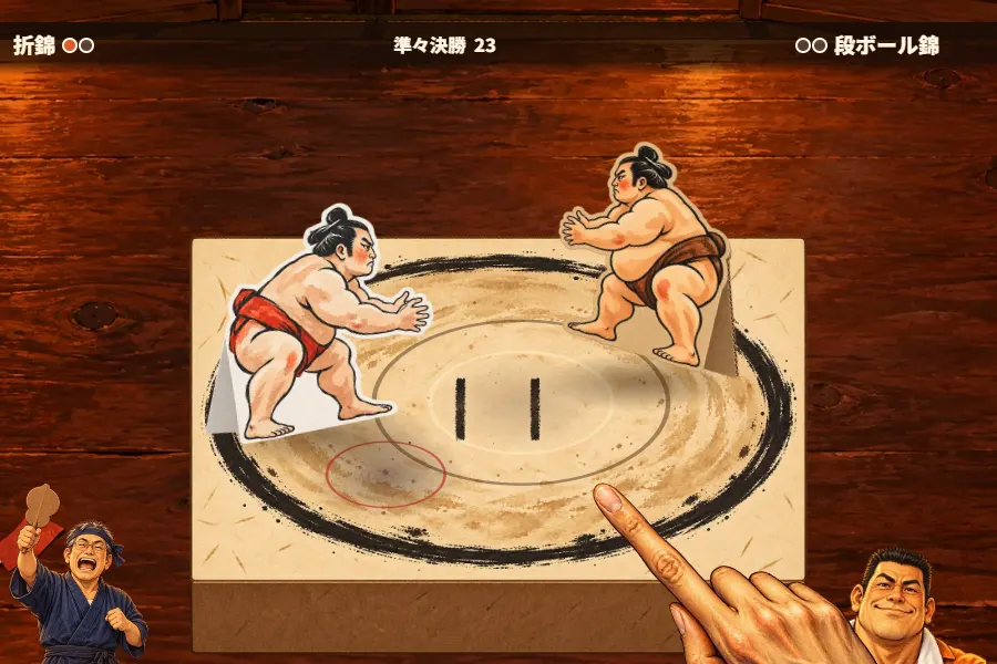 居酒屋の座卓の上の厚紙の箱を斜め上から見たゲーム画面。箱のふたに描かれた俵の円の中で、紙を折って立てた力士2体が向かい合っている