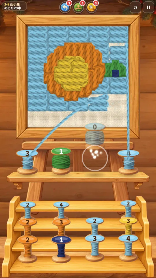 スマホの縦画面。額の毛糸の絵から水色の毛糸が棚の糸巻きへのび、下の階段状の台に色ちがいの糸巻きが並ぶ