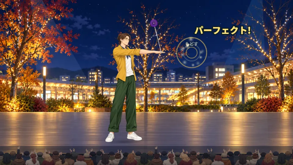 横画面。電飾の木が光る夜の広場のステージで、パフォーマーが腕を前にのばし、ヨーヨーを頭の上まで大きく円をえがいて回している。手前には観客の後ろ姿